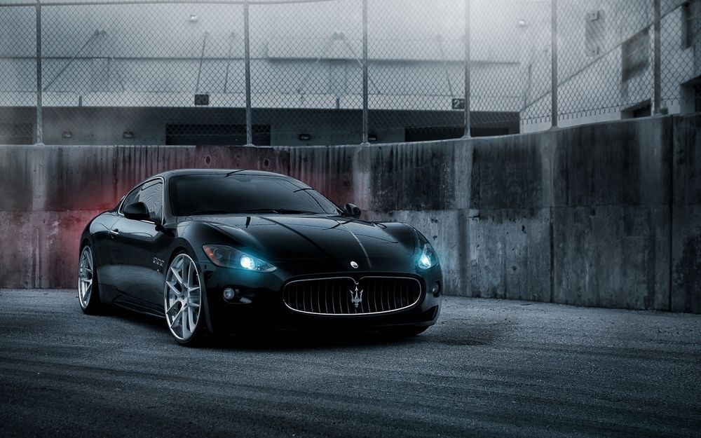 Обои для рабочего стола Черный Maserati на фоне забора с сеткой
