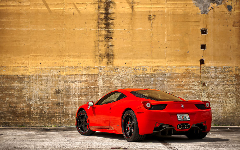 Обои для рабочего стола Ferrari на фоне желтой стены здания (вид сзади)