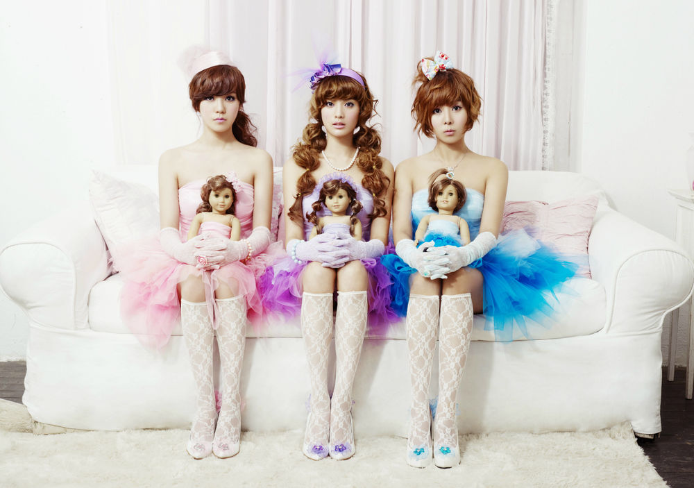 Обои для рабочего стола Группа Orange caravel, k-pop, три азиатки с куклами в кружевных гольфах сидят на белом диване, Южная Корея