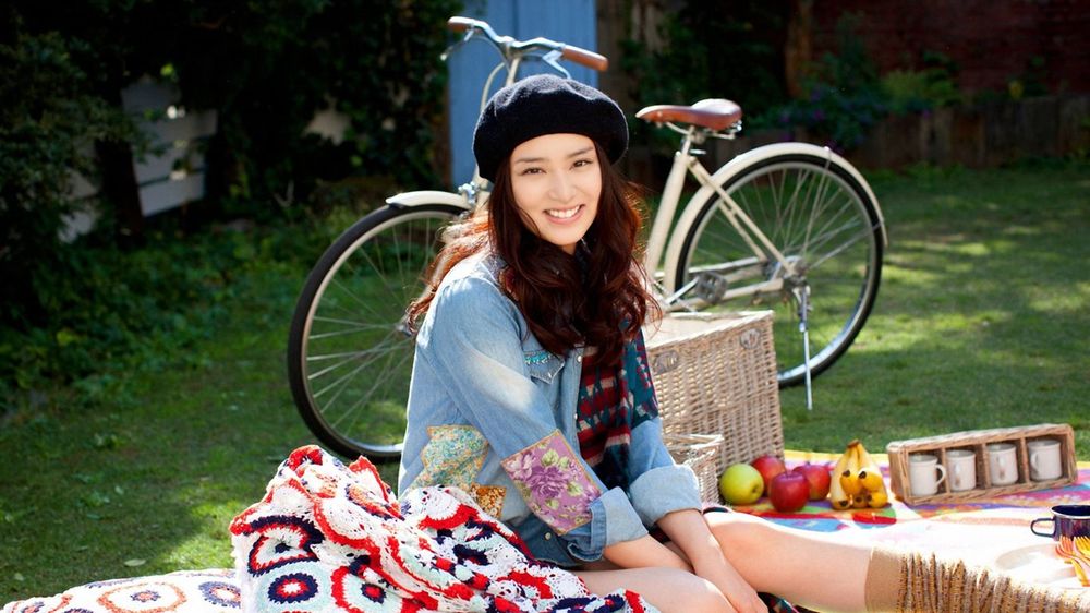 Обои для рабочего стола Девушка на пикнике, фрукты, чашки, корзина на траве рядом с велосипедом
