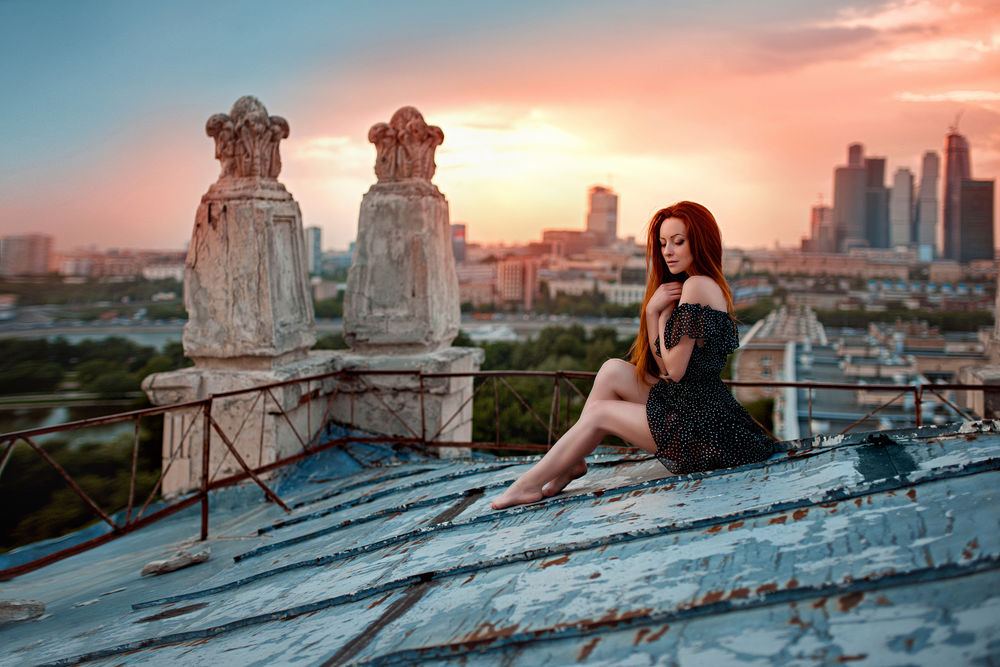 Обои для рабочего стола Рыжеволосая девушка сидит на крыше здания с видом на город