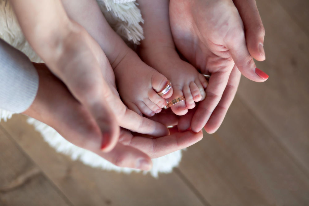 Обои для рабочего стола Семейное счастье, ладони отца и матери держат детские ножки, на пальчиках которых обручальные кольца