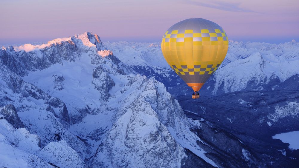 Обои для рабочего стола Воздушный шар летит над заснеженными горами