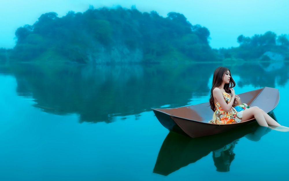 Обои для рабочего стола Девушка азиатка сидит в лодке плавающей по озеру