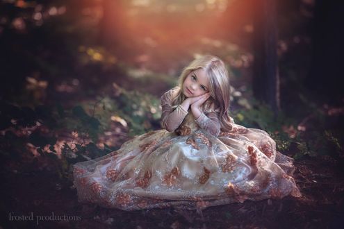 Обои на рабочий стол Sleeping Beauty Aurora Costume - Peach Dress Maleficent Movie / Девочка в костюме из фильма Maleficent сидит на поляне прижав к щеке сложенные вместе ладошки, автор Frosted Productions