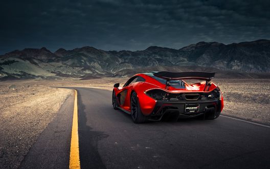 Обои на рабочий стол Красный Hypercar едет по дороге в направлении гор
