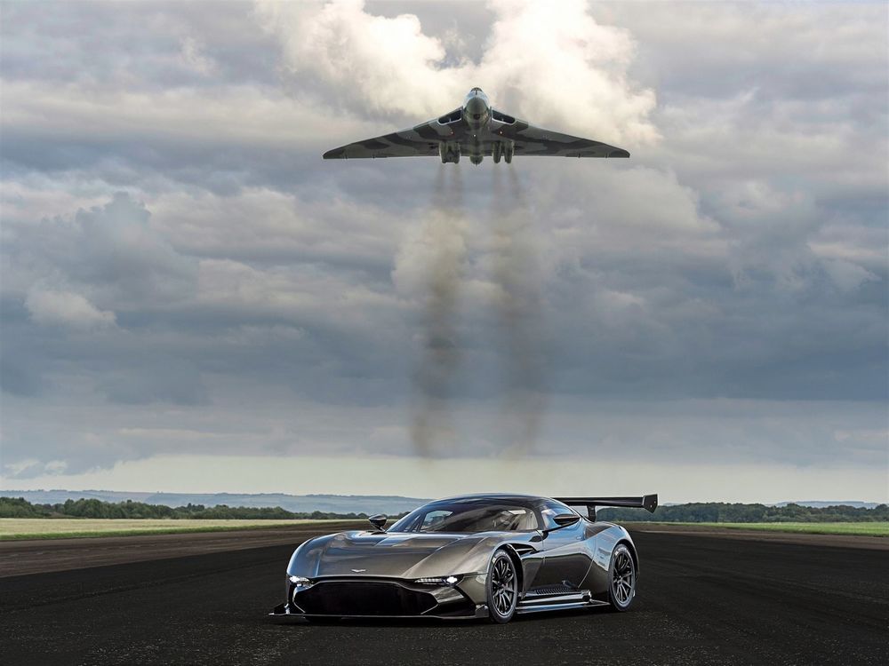 Обои для рабочего стола Aston Martin на аэродроме, над ним летает истребитель