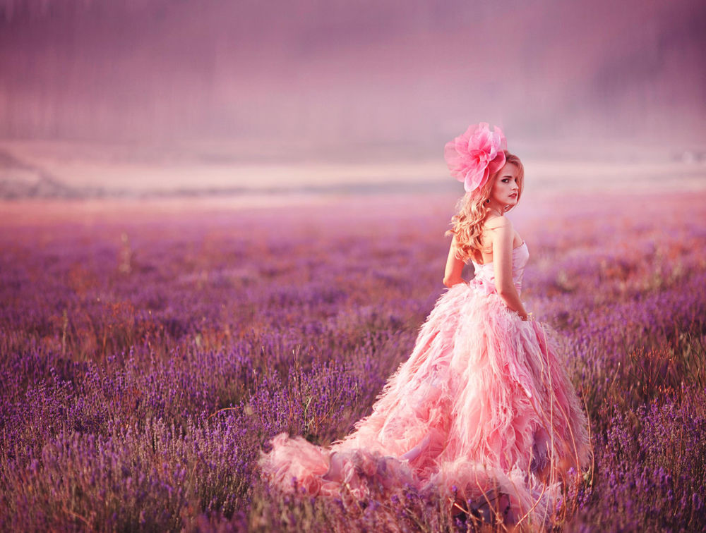 Обои для рабочего стола Девушка с цветком в волосах стоит на лавандовом поле