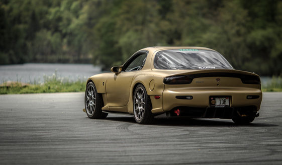 Обои на рабочий стол Автомобиль марки Mazda RX-7 JDM стоит на дороге возле воды