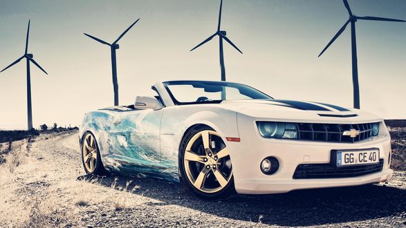 Обои на рабочий стол Белый автомобиль с Chevrolet Camaro с аэрографическим рисунком виде морской волны, стоит на песчаной дороге на фоне ветряков и неба