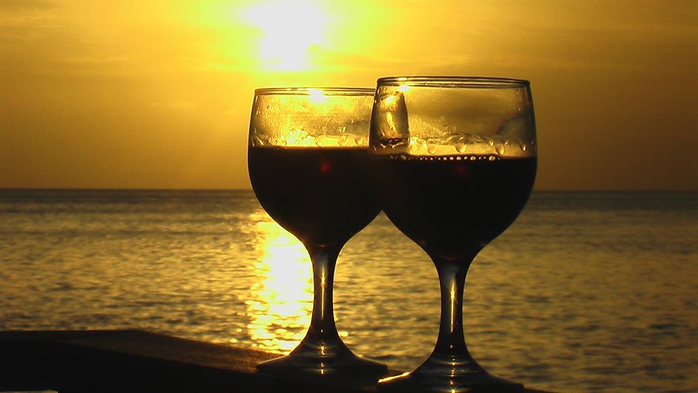 Обои для рабочего стола Два бокала с вином на фоне моря и неба на закате