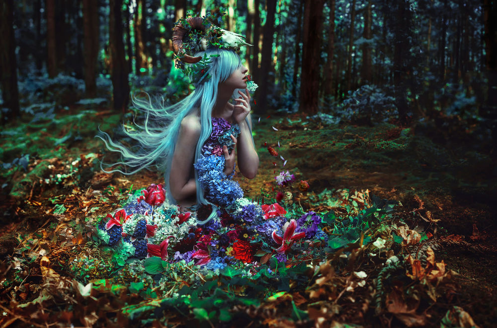 Обои для рабочего стола Девушка с черепом животного на голове в цветочном платье сидит в лесу на сухих листьях, Kindra Nikole