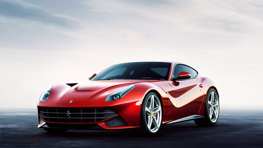 Обои для рабочего стола Красный автомобиль Ferrari стоит на дороге на фоне неба