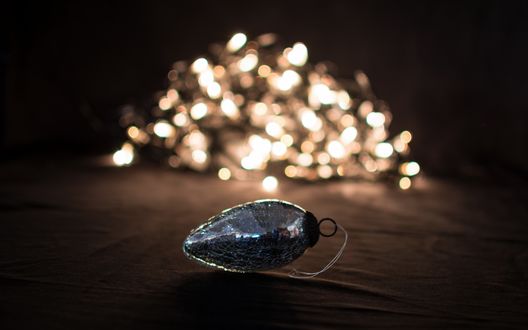 Обои на рабочий стол Новогодняя игрушка на фоне горящих огоньков гирлянды