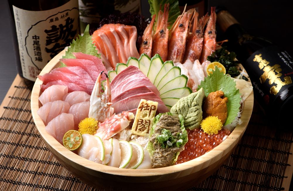Обои для рабочего стола Японская кухня, свежие сырые ломтики мяса и рыбы с креветками и икрой в большой тарелке, рядом бутылки сакэ