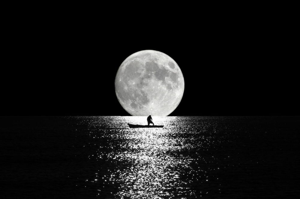 Обои для рабочего стола Мужчина в лодке на воде, на фоне полной луны