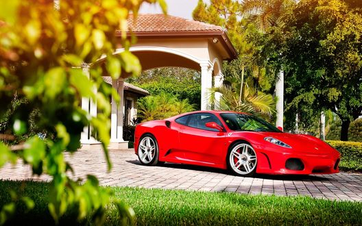 Обои на рабочий стол Красная Ferrari 430 Scuderia на фоне зеленых деревьев