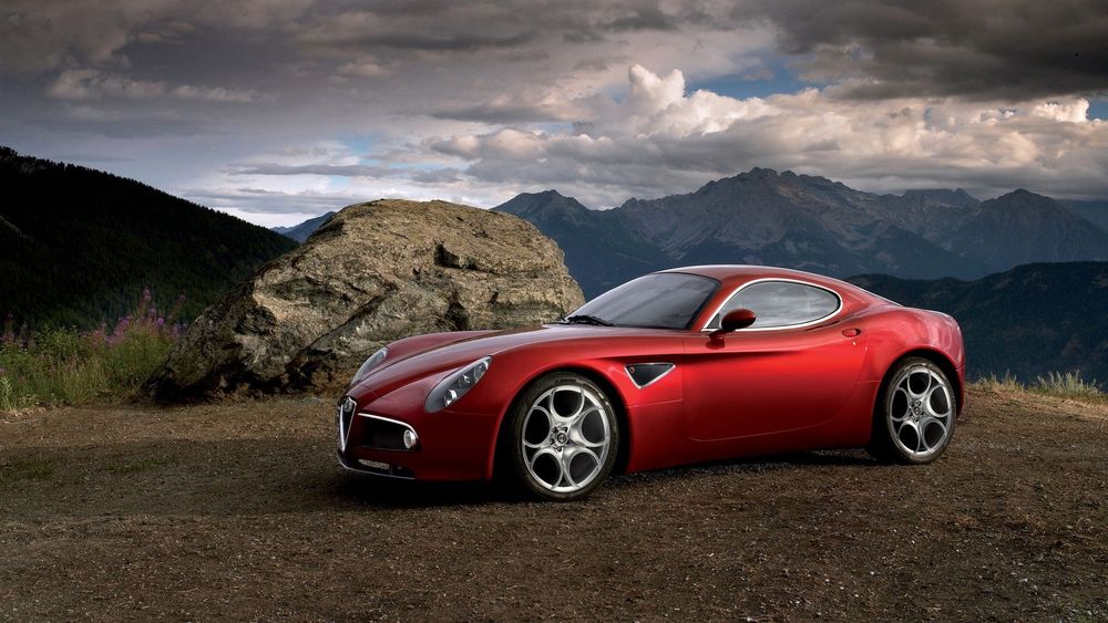 Обои для рабочего стола Красный итальянский спорткар Alfa Romeo 8C Competizione 2007 стоит на фоне гор