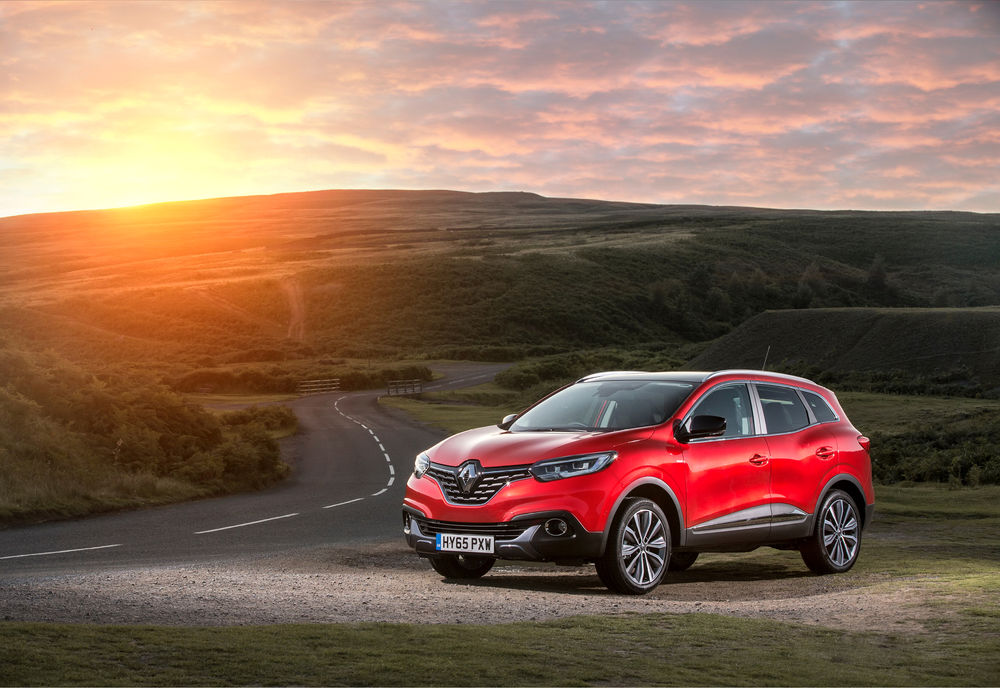 Обои для рабочего стола Красный внедорожник Renault на фоне зеленых холмов и прекрасного заката солнца