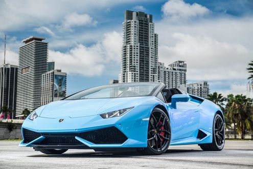 Обои на рабочий стол Lamborghini Huracan Spyder, 2016 года, бирюзового цвета на фоне города и высотных домов