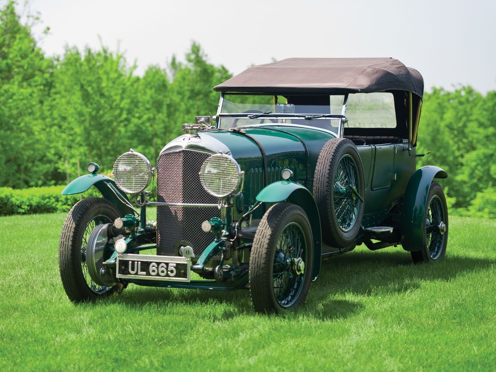 Обои для рабочего стола Автомобиль 1929-1930 Bentley 4 ВЅ Litre Vanden Plas Open Tourer на зеленой поляне на фоне леса размытый фон