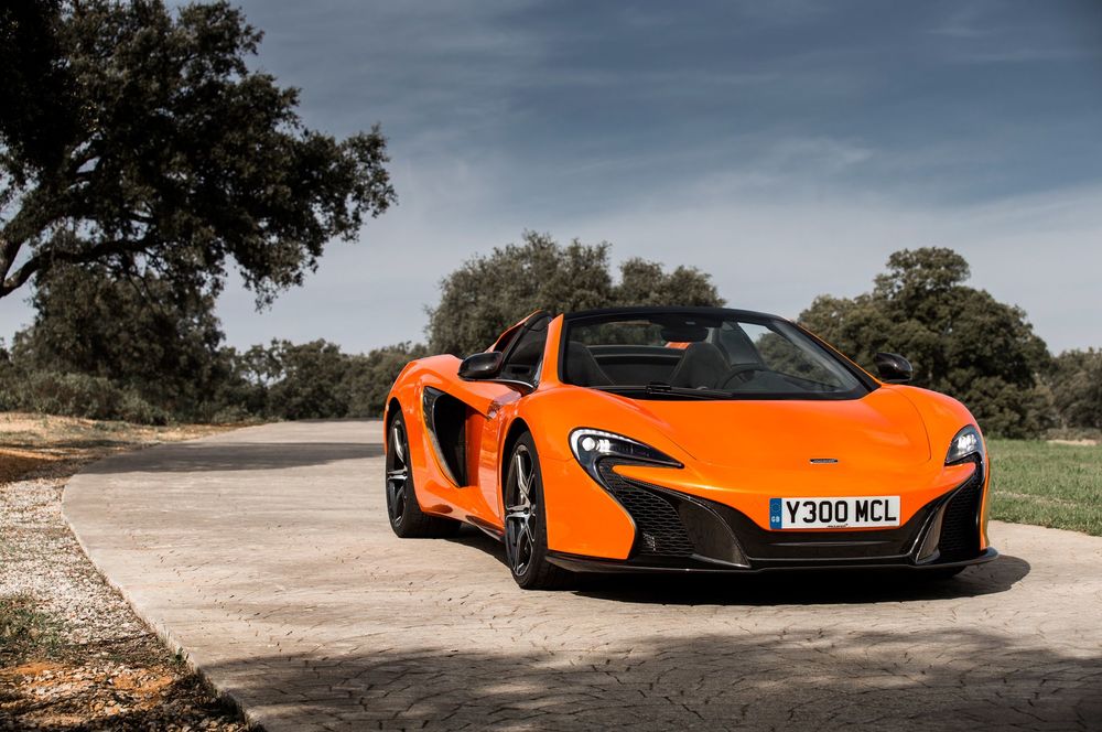 Обои для рабочего стола McLaren 650S Spider, 2015 года, оранжевого цветв на фоне дороги и деревьев