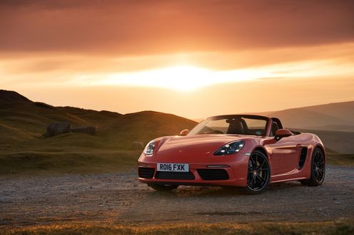 Обои на рабочий стол Кабриолет Porsche 718 Boxster, 2016 года, оранжевый металлик, на фоне равнины и прекрасного заката солнца