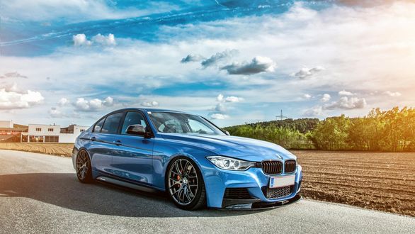 Обои на рабочий стол Синий автомобиль BMW F30 стоит на дороге, на фоне неба в облаках, промышленного здания, поля и деревьев