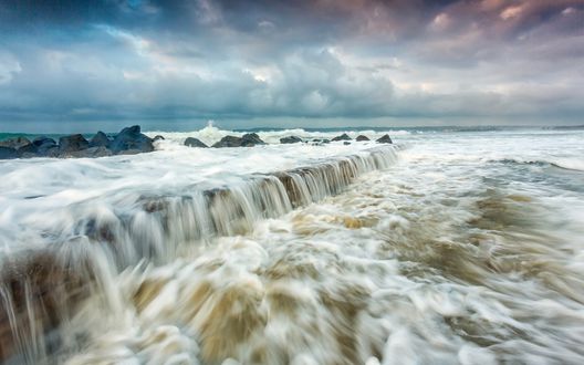 Обои на рабочий стол Водяной порог в море на фоне неба, затянутого сине-розовыми тучами
