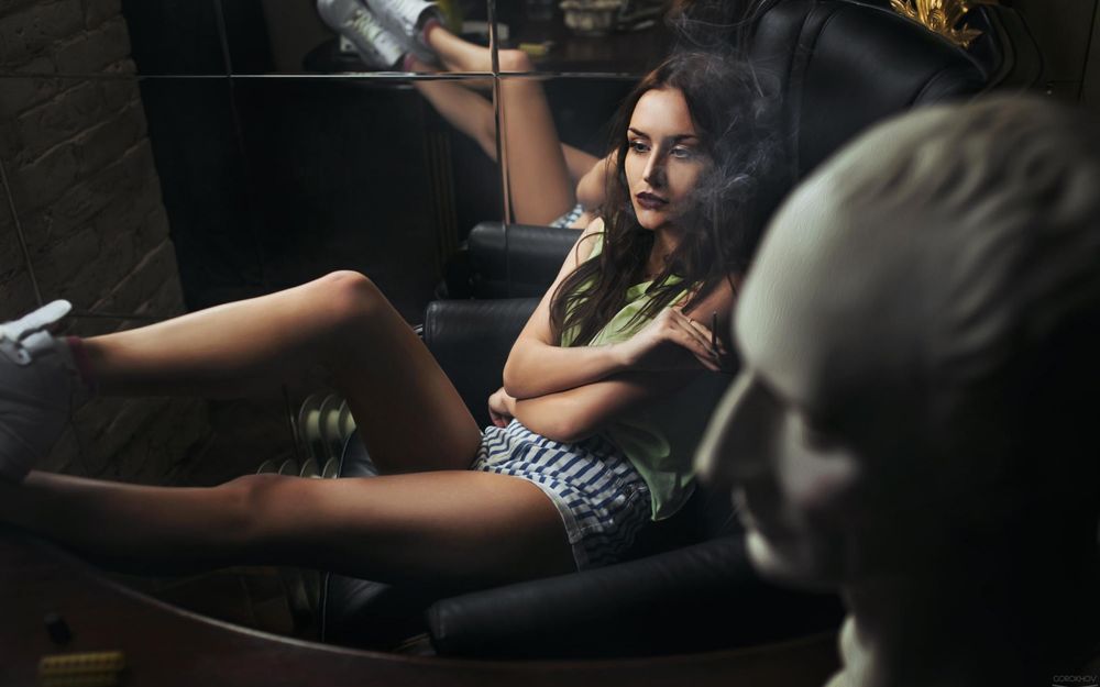 Обои для рабочего стола Девушка сидит в кресле и курит сигарету, рядом стоит белая скульптура, фотограф Иван Горохов / Gorokhov