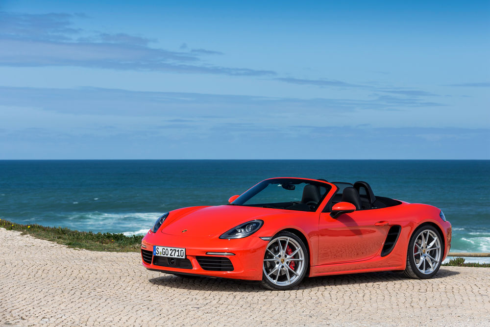 Обои для рабочего стола Красный кабриолет 2016 года Porsche 718 Boxster стоит на побережье на фоне моря и голубого неба