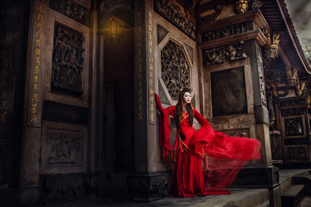 Обои для рабочего стола Азиатка в красном платье позирует в старом храме