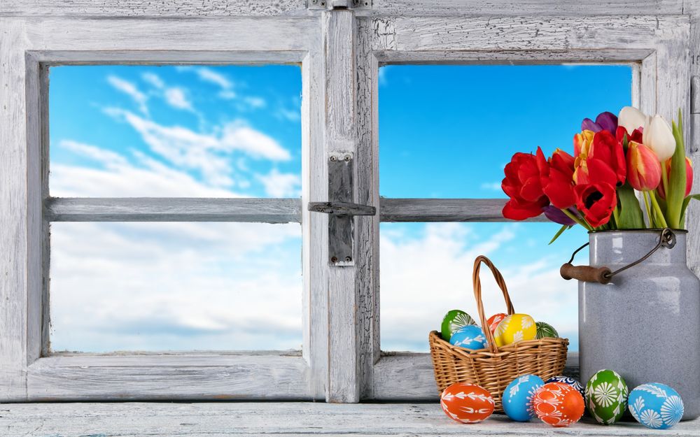 Обои для рабочего стола Корзинка с пасхальными яйцами и букет разноцветных тюльпанов стоят на подоконнике