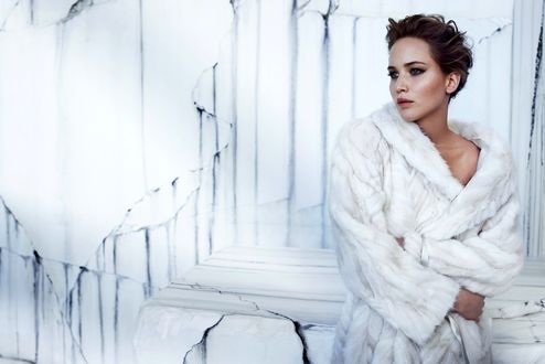 Обои на рабочий стол Дженифер Лоуренс / Jennifer Lawrence с короткой стрижкой стоит в белой шубе у белой стены с трещинами