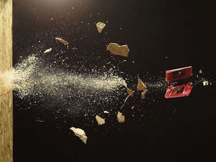 Обои на рабочий стол Красный сотовый телефон разбит вдребезги о стену
