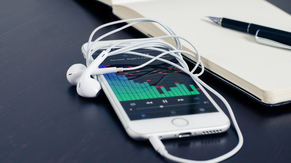 Обои на рабочий стол Белый смартфон с включенным эквалайзером, рядом блокнот и ручка