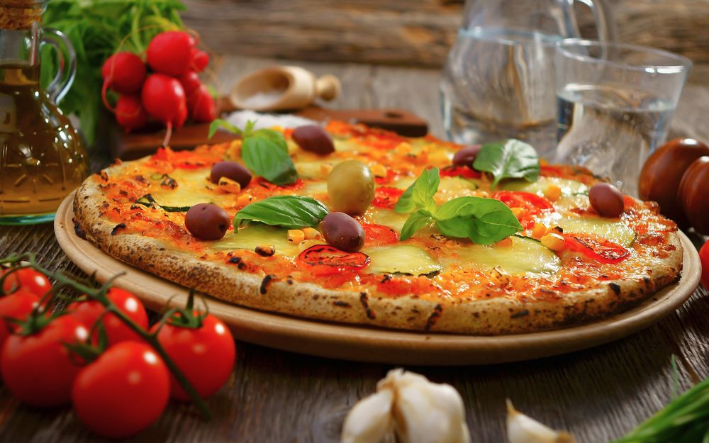 Обои для рабочего стола Пицца украшенная оливками и зеленью, чеснок, помидоры, кувшинчики с соусом
