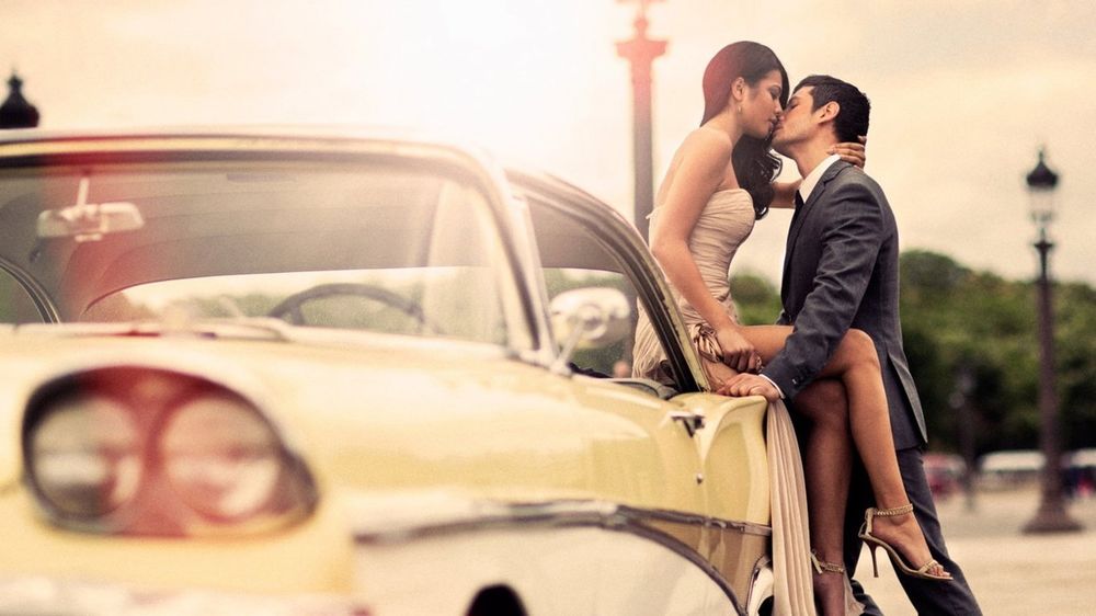 Обои для рабочего стола Девушка с мужчиной целуются, девушка сидит на капоте авто