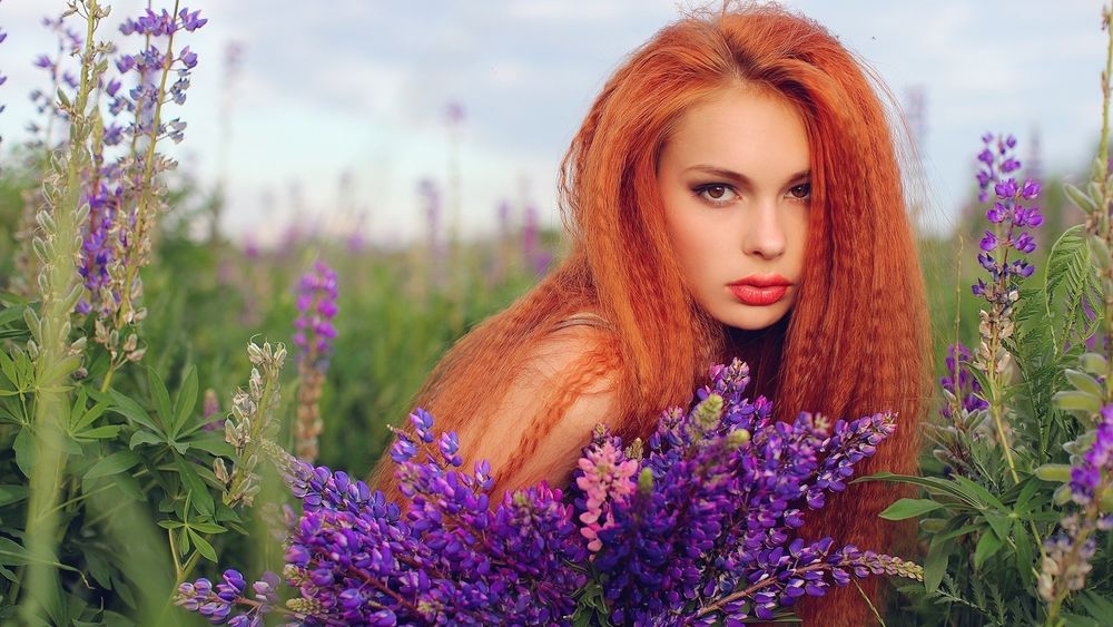 Обои для рабочего стола Рыжеволосая девушка с букетом люпинов