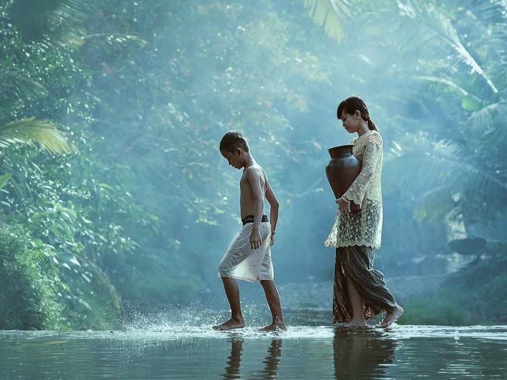 Обои для рабочего стола Женщина и ребенок переходят ручей ранним утром в лесу, в руках у нее кувшин для воды