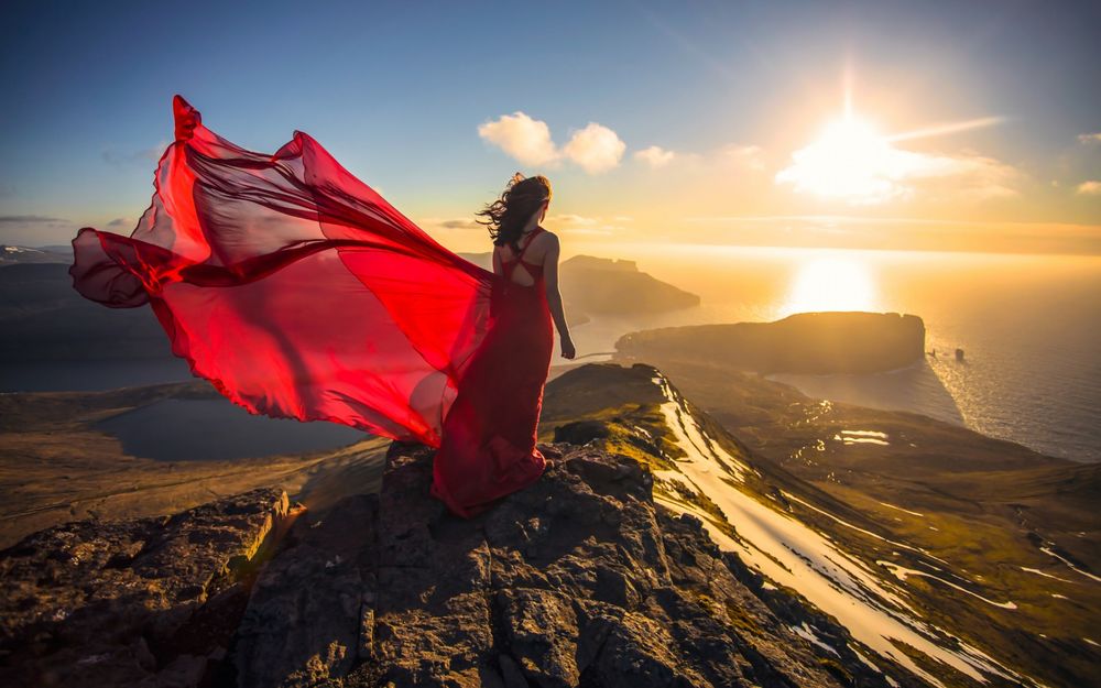 Обои для рабочего стола Дания, Фарерские острова, девушка в красном платье стоит на горе и смотрит на закат солнца над Атлантическим океаном
