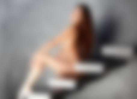 Обои на рабочий стол Обнаженная испанская модель Lorena Garcia / Лорен Гарсия сидит расставив ноги на декоративных ступенях на фоне серой стены