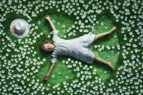 Обои на рабочий стол Девочка лежит на поляне с ромашками, фотограф John Wilhelm