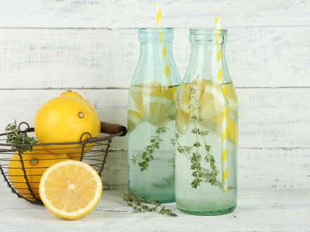 Обои на рабочий стол Лимоны в корзинке, две бутылки с лимонной водой и трубочками