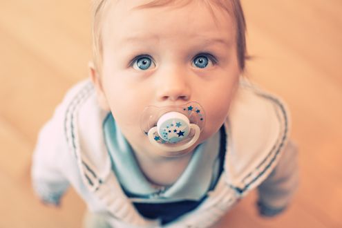 Обои на рабочий стол Ребенок с пустышкой во рту смотрит вверх