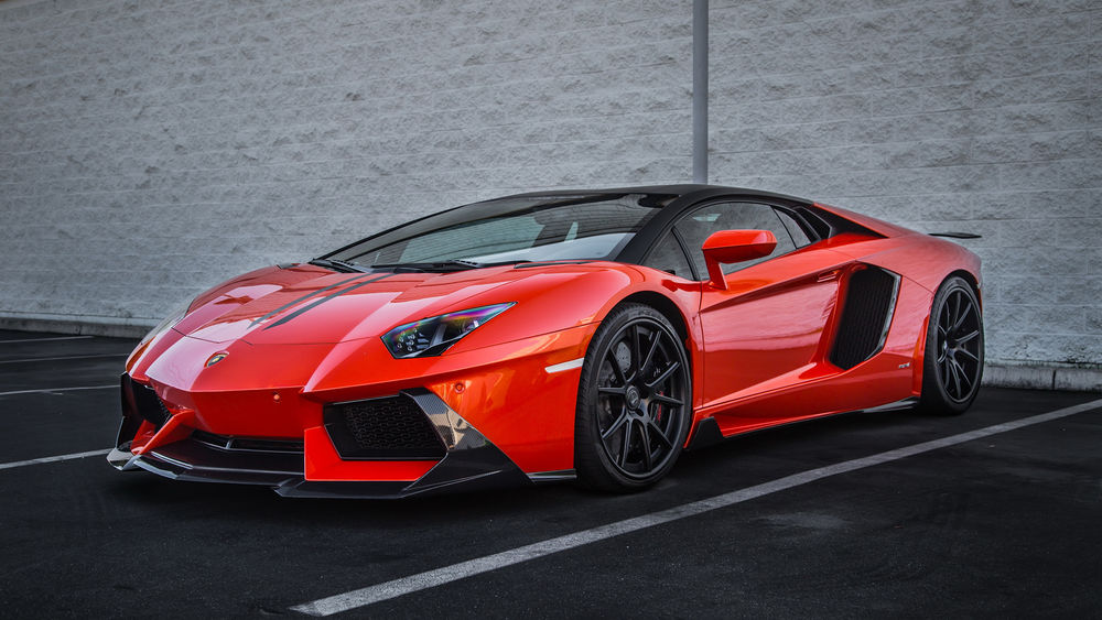Обои для рабочего стола Красный Lamborghini на парковке у здания из белого кирпича