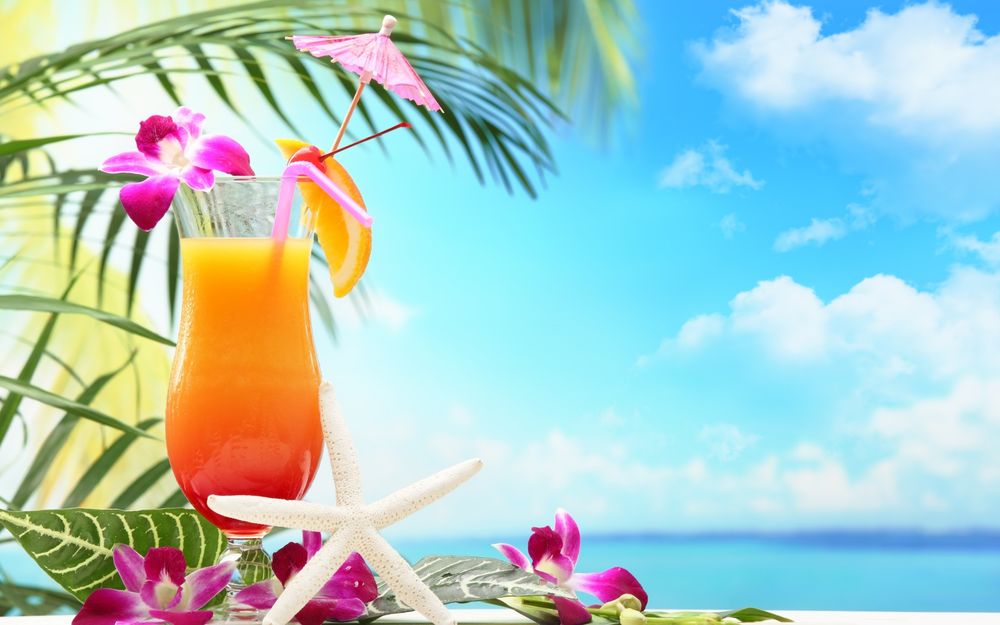 Обои для рабочего стола Апельсиновый тропический коктейль с цветами орхидеи и зонтиком на фоне моря и пальмы