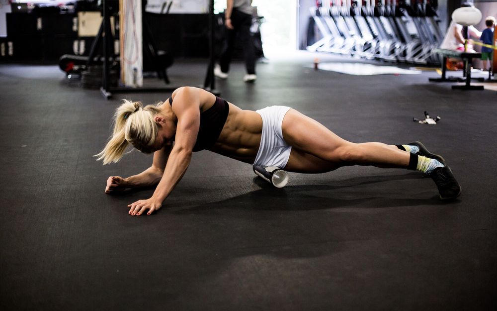 Обои для рабочего стола Блондинка приняла упор лежа в спортзале на полу и делает упражнение