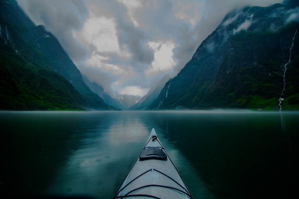Обои для рабочего стола Байдарка плывет по реке в горной местности, в пасмурную погоду, Norway / Норвегия