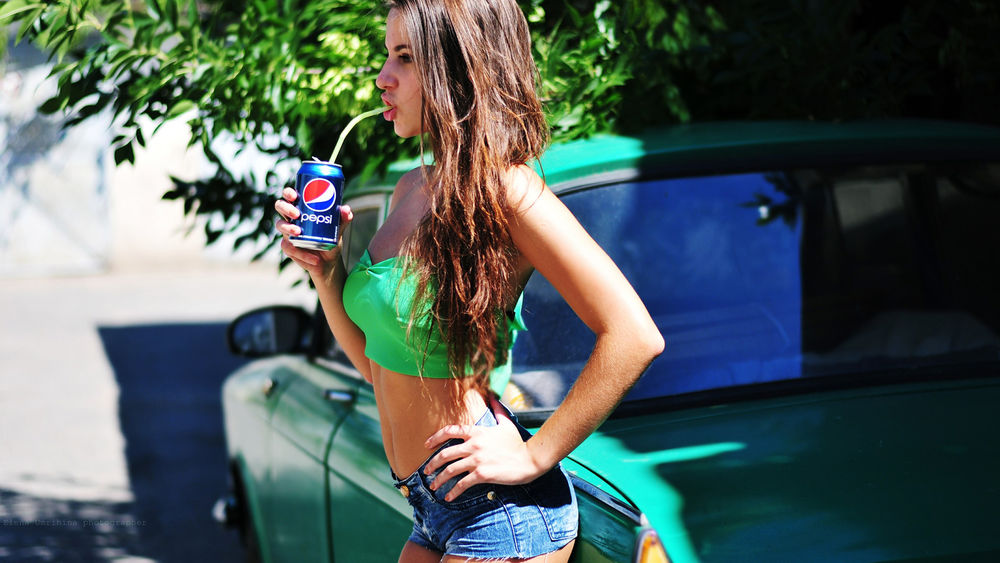 Обои для рабочего стола Девушка с баночкой Pepsi возле зеленого авто